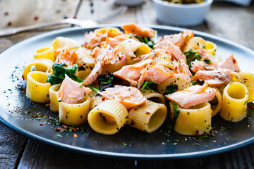 Pasta with salmon and spinach on wooden background