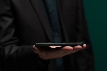 Man in dark shirt and jacket holds smartphone