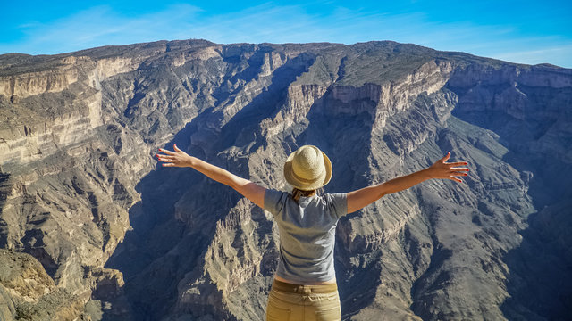 Young Foreign Female Tourist Enjoying the View of Wadi Ghul aka Grand Canyon of Oman in Jebel Shams Mountains. Woman in Active Solo Travel in Middle East Countries