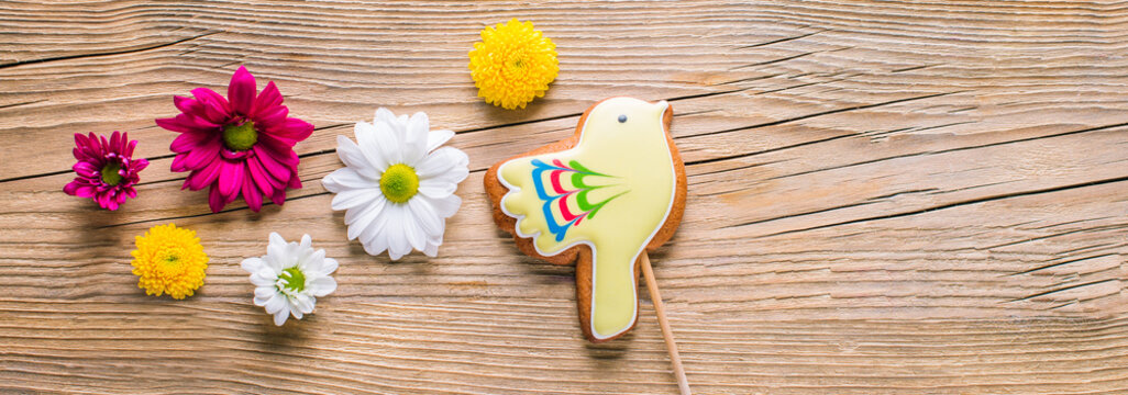 Easter gingerbread in the shape of a yellow bird on a wooden background, long banner