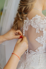 A young bride buttoned wedding dress. Happy wedding day.