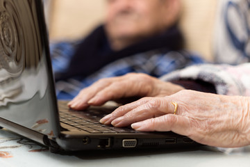 Hands of senior woman typing on laptop