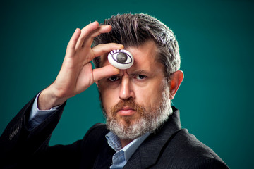 A portrait of man in suit holding egg with drawing eye near forehead. Third eye concept