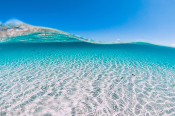 Turquoise ocean water with sandy bottom underwater.