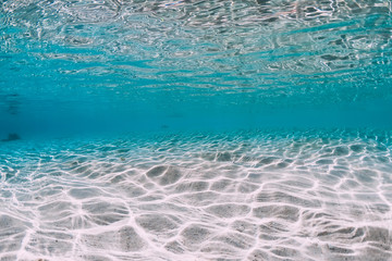 Turquoise ocean water with sandy bottom underwater.
