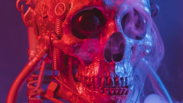 Robotic skull in red and blue light with smoke