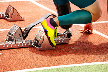 Prosthesis close-up of disabled person competition on the stadium track prepared to start racing