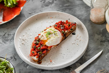 Sandwich with red fish, poached egg, balsamic vinegar and micro-greens