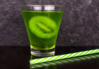  Green drink with kiwi slice in a glass on a black background.