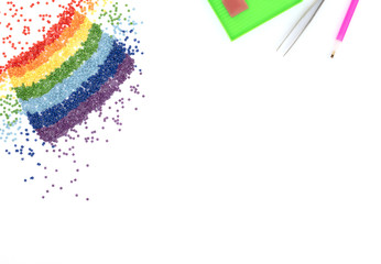 The rainbow of colorful crystals, tweezers, stylus and tray for diamond embroidery, mosaic on white...