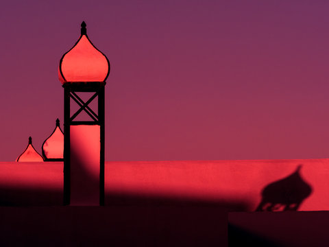 Roof top architecture with onion domes are lit by a red sunset light and dramatic shadows are cast.Image