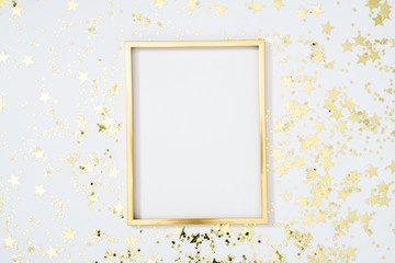 Gold frame with gold stars on white background. Flat lay, top view, copy space - obrazy, fototapety, plakaty