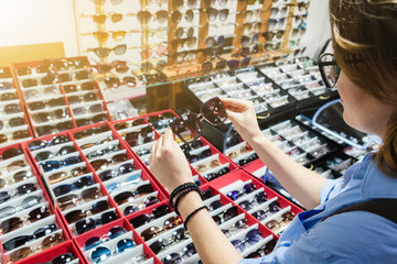 Woman chooses sunglasses in a store