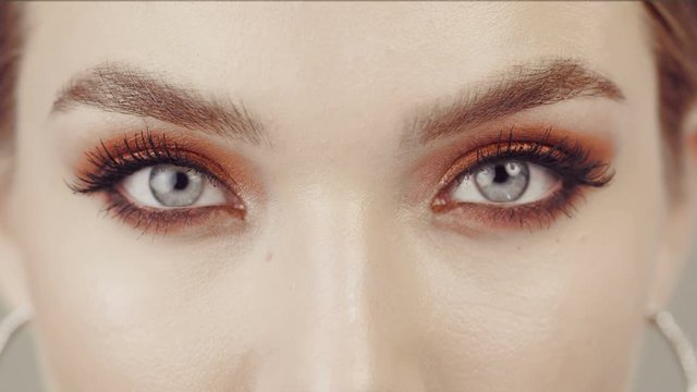 Female eyes with bright orange make up. Mascala. Look at the camera. Good eyesight. 