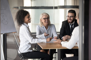 Multinational cheerful office workers chatting at briefing in conference room