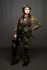 A girl soldier in camouflage clothing poses in a Studio