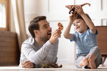 Happy young man playing toys with joyful small schoolboy.