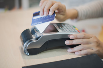 Hand of young woman seller using card reader for payment of a credit card. Accept payment by credit card technology at retail shop. Cashless Payment concept.