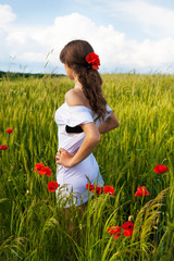 Beautiful girl in a white dress standing in a wheat field