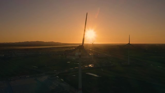 Sagome di pale eoliche che girano al tramonto in citt&agrave;. Sfondo anonimo del cielo.