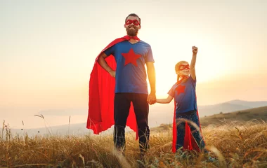 Foto op Plexiglas concept of father's day. dad and child daughter in hero superhero costume at sunset  . © JenkoAtaman