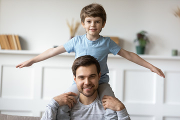 Fototapeta na wymiar Joyful father holding on shoulders happy child son.