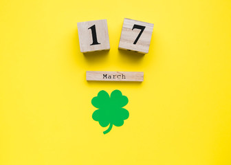 St Patricks Day card. Shamrocks and leprechaun hat on yellow background. Date of 17 March on wooden calendar. st paddy's day concept