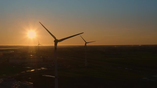 Sagome di pale eoliche che girano al tramonto in citt&agrave;. Sfondo anonimo del cielo.