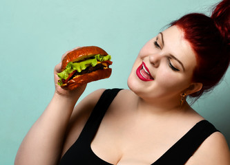 Happy size-plus overweight fat woman happy hold burger cheeseburger barbeque sandwich with beef  on pastel turquoise
