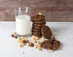 Chocolate cookies for breakfast with mint and hazelnut and a glass of milk on a gray table