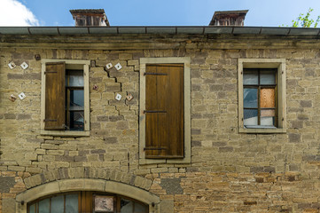 Altes baufälliges Haus mit Scheune aus hellem Sandstein mit südländischem Flair bei blauem Himmel und Sonnenschein mit zerbrochenen Fensterscheiben und Fensterladen aus Holz