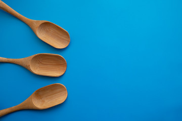 Eco bamboo wooden spoons on the blue table. Empty space for design