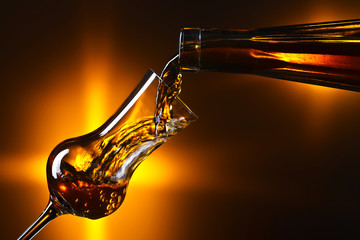 Strong alcoholic drink is poured into a glass.