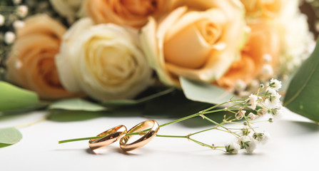 Wedding rings on branch with roses on white background