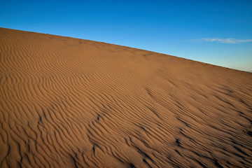 Abstract of textured sand dune against blue sky. Corralejo, Fuerteventura, Spain.