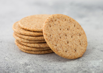 Stack of various organic crispy wheat crackers with sesame and salt on light kitchen table background.