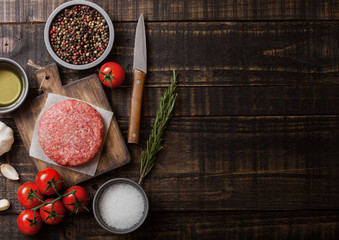 Raw minced homemade grill beef burger with spices and herbs. Top view and space for text.On top of chopping board and kitchen table background. With pepper salt and garlic.