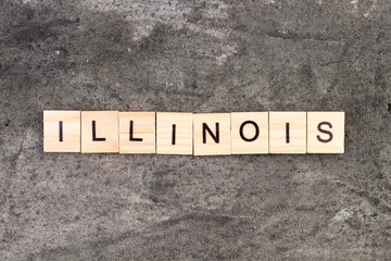 Illinois word written on wood block, on gray concrete background. Top view.