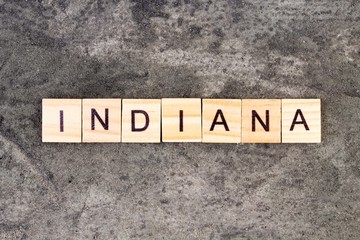 Indiana word written on wood block, on gray concrete background. Top view.