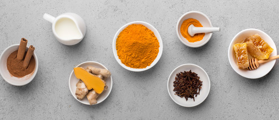 Curcuma root, cinnamon, ginger, milk on concrete background