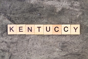 Kentucky word written on wood block, on gray concrete background. Top view.