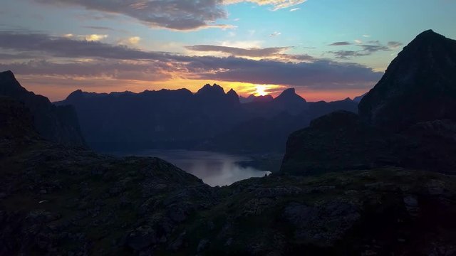 Flying over the mountains and fjord. Beautiful sunset and dramatic sky in the mountains. Lofoten Islands. Norway. 4K