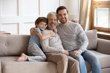 Portrait of smiling joyful multigenerational male family resting on couch.