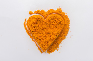 Heap ground turmeric isolated in heart shape on white