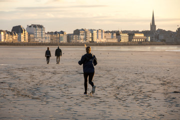  Woman is running  along the beach in Saint-Malo, Brittany, France