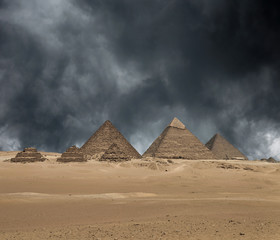 The Giza pyramid complex under dramatic grey stormy sky