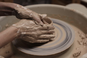 female hands in clay on a pottery wheel close-up