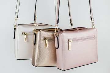 Tres bolsos colgando. Blanco dorado y rosa.