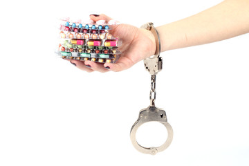 pills and tablets handcuffed hands on white background