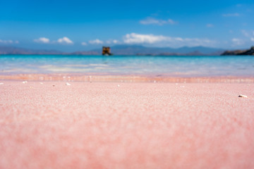 close up shot of pink beach with blue water in indonesia on komodo islands